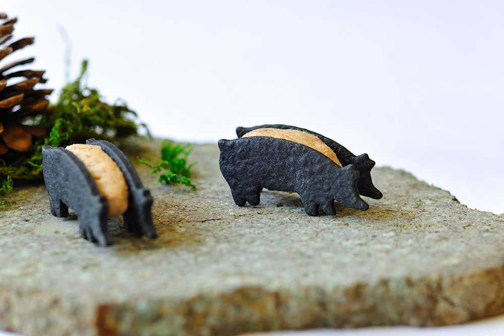 黒豚のリエットを竹炭のサブレで挟んだアミューズ。器は佐渡金銀山の岩盤で作った特注品。